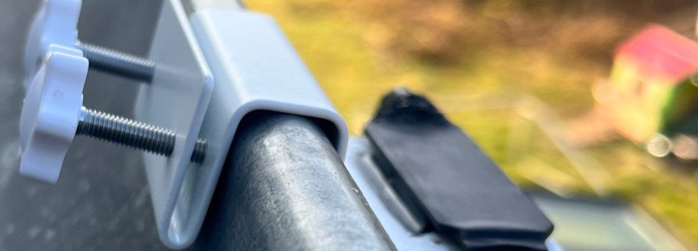 Close-up of the clamp bracket and thumbscrews on the front edge of a gutter